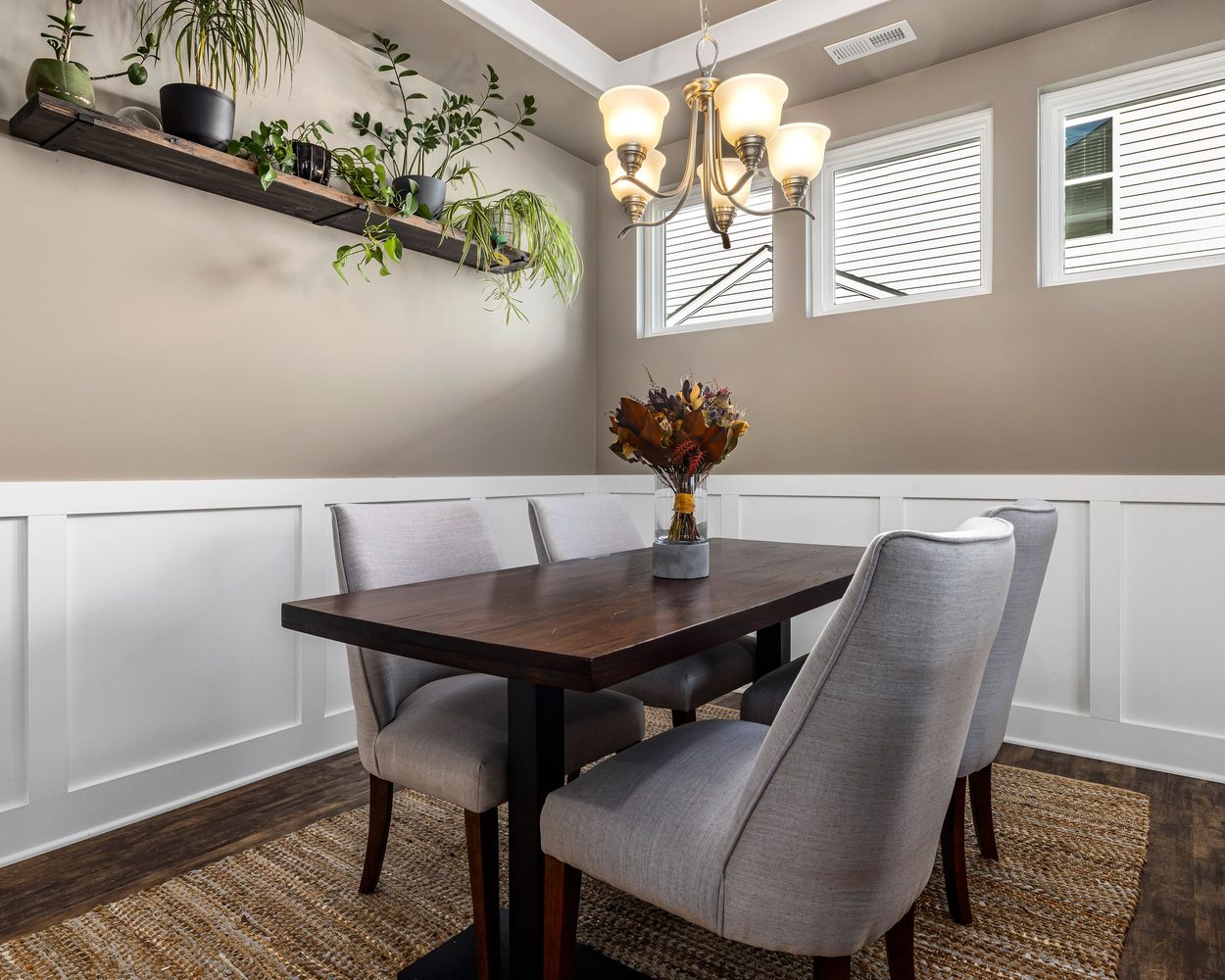 Warm neutral dining room with paneled wall molding, a set table and soft daylight