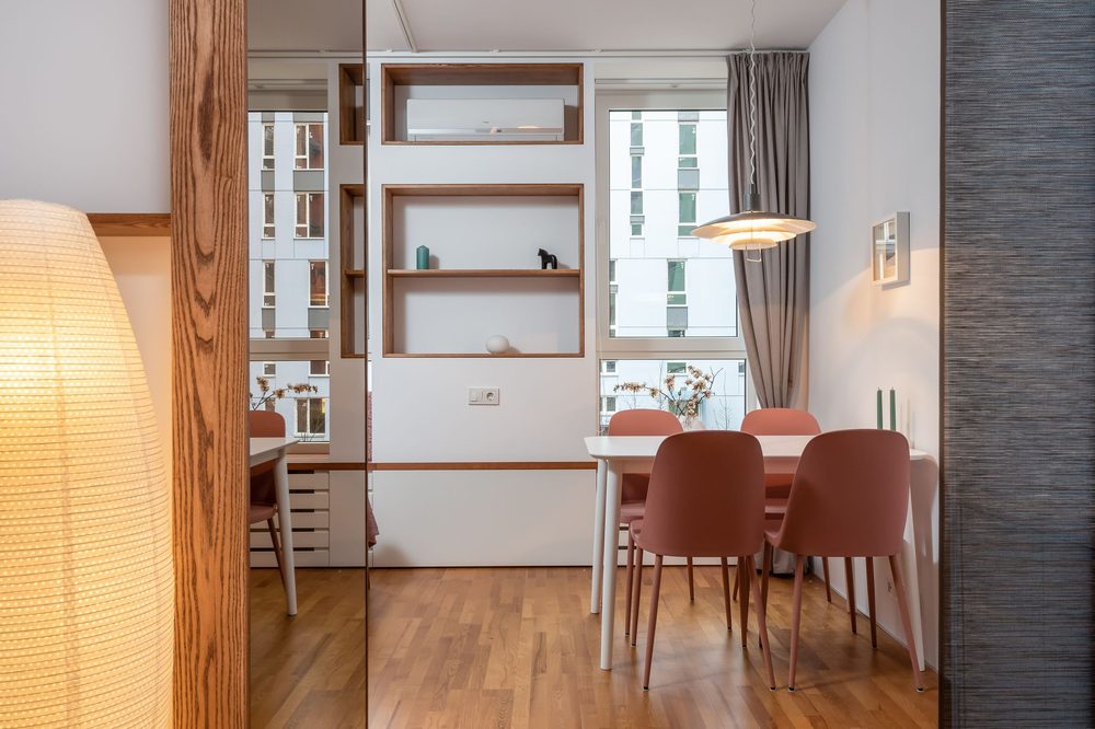 Contemporary dining area with a grey grasscloth textured wall, coral chairs and open shelving