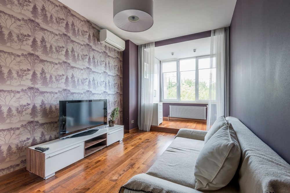Living room with a soft forest-toile wallpaper wall, low media unit and daylight window
