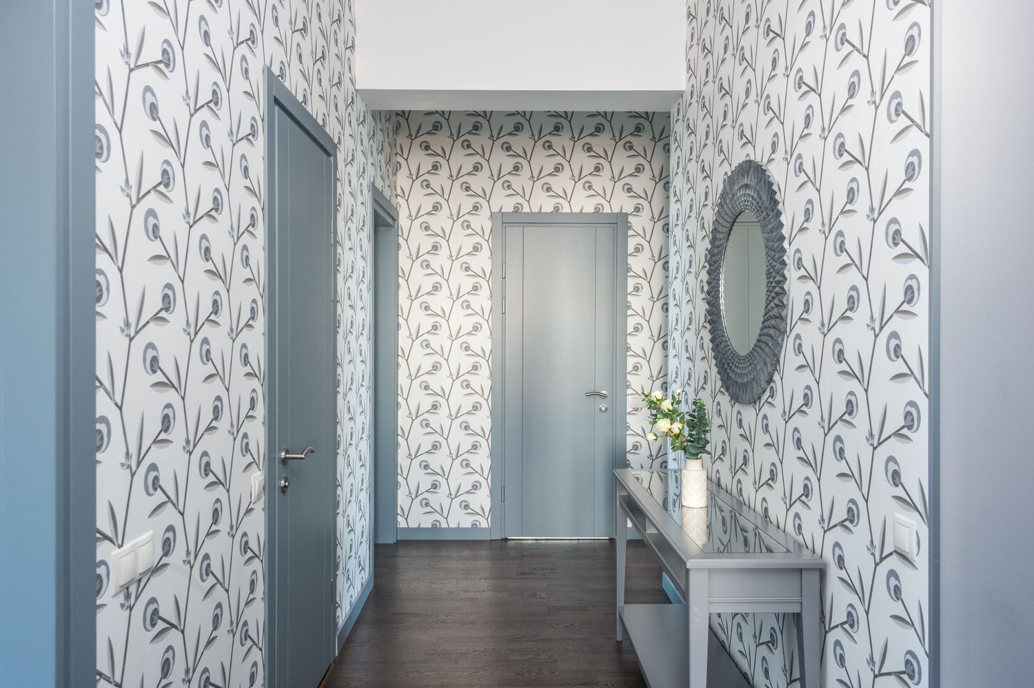 Bright entryway hallway finished with a soft grey botanical wallpaper, console table and mirror