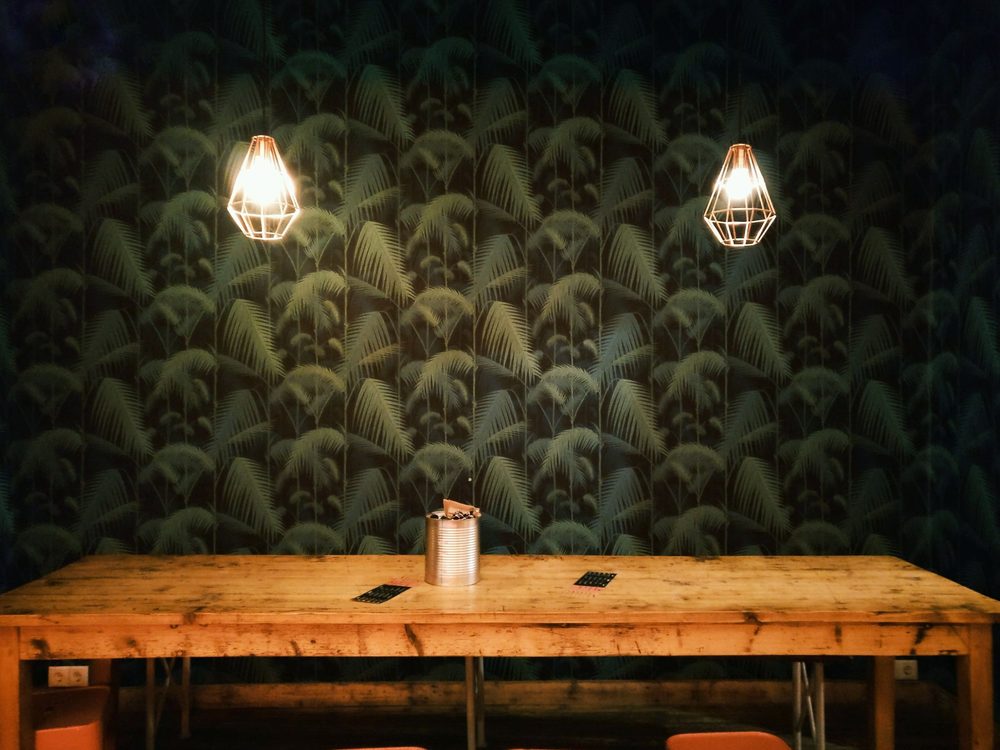 Commercial café interior with a dark botanical patterned wall and pendant lights