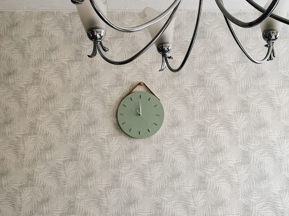 Wall finished in a neutral decorative wallpaper pattern beneath a chandelier
