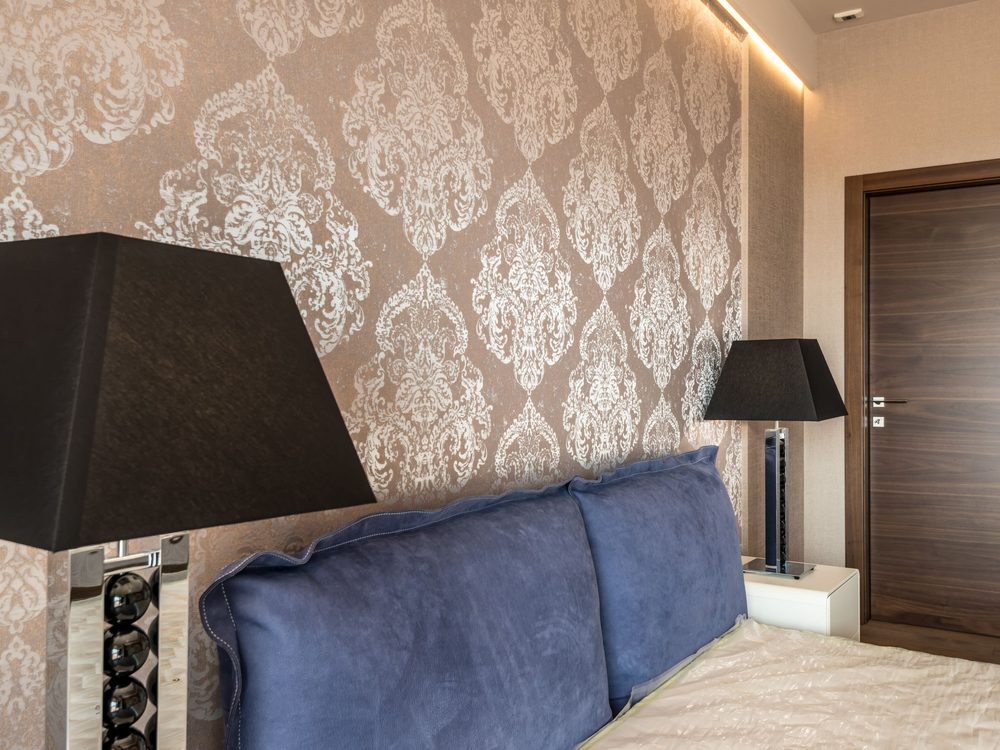 Residential bedroom with beige damask wallpaper and blue accent seating